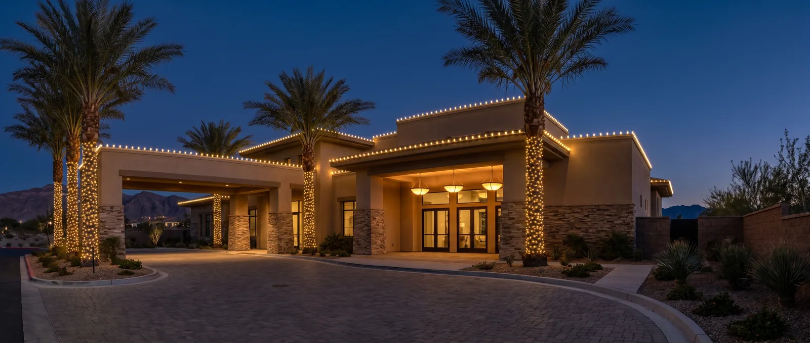 Private clubhouse at blue hour with C9 bulbs along the full roofline, wrapped palms and warm entry lights